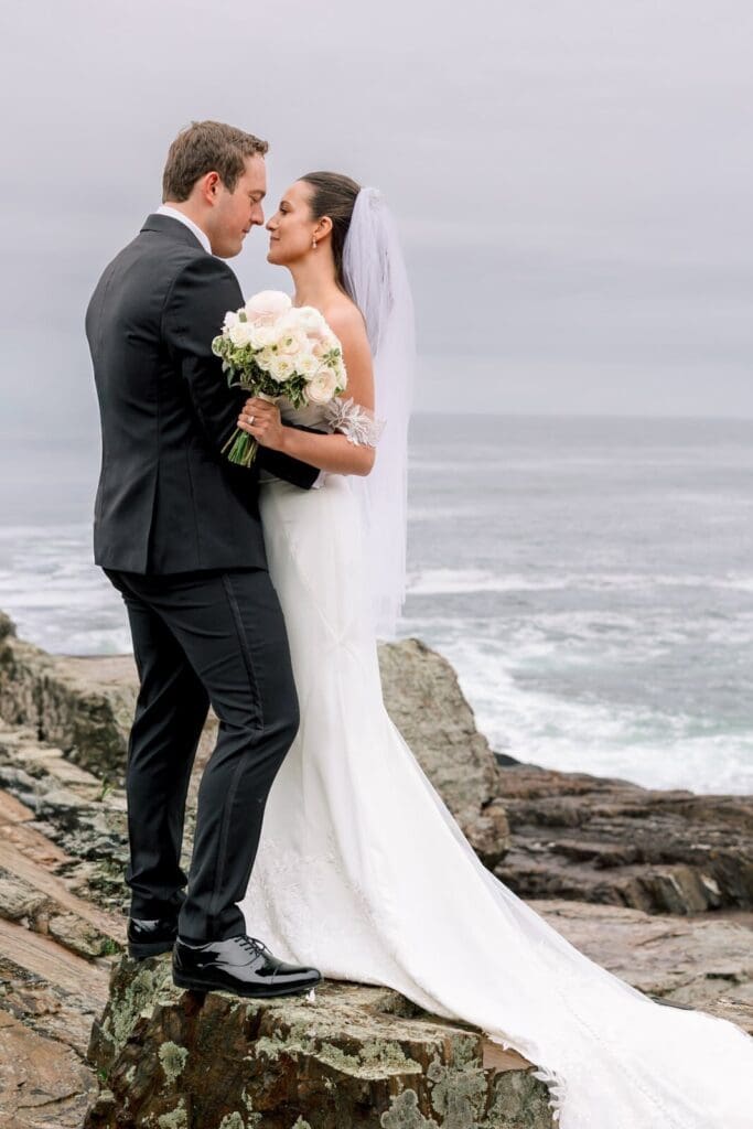 A close up of a bride and groom posing on cliffside rocks on their wedding day in New England